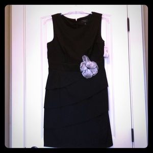 Black cocktail dress with flower embellishment.